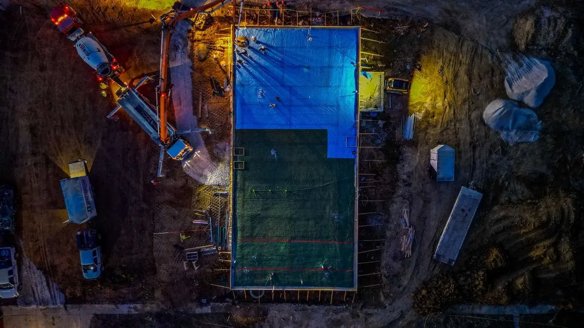Nighttime top-down view of concrete pour with pump truck and work lights
