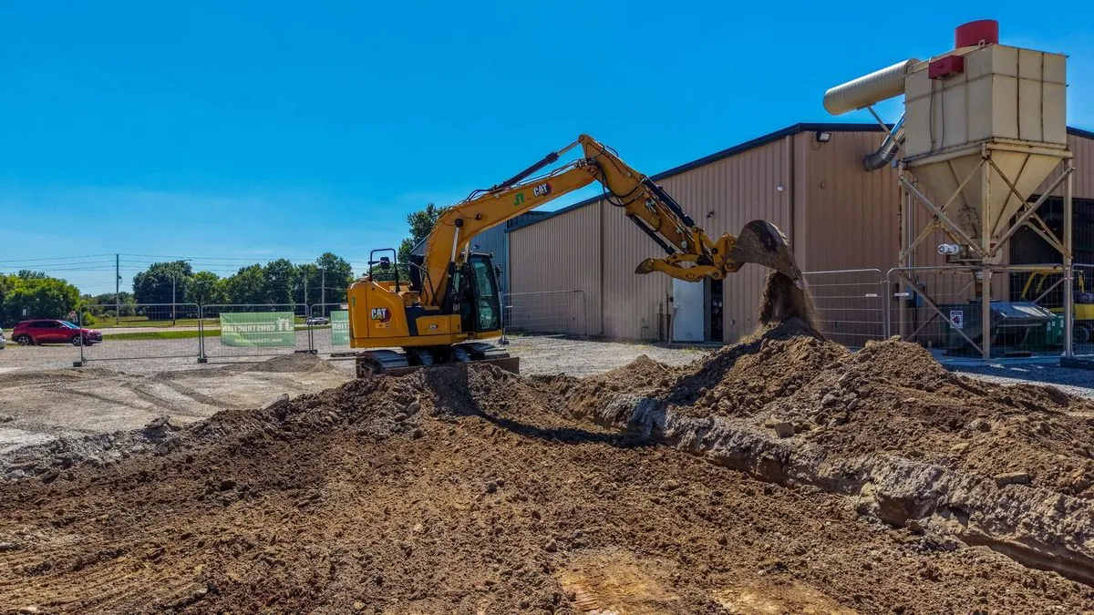 Excavator dumping dirt under blue sky