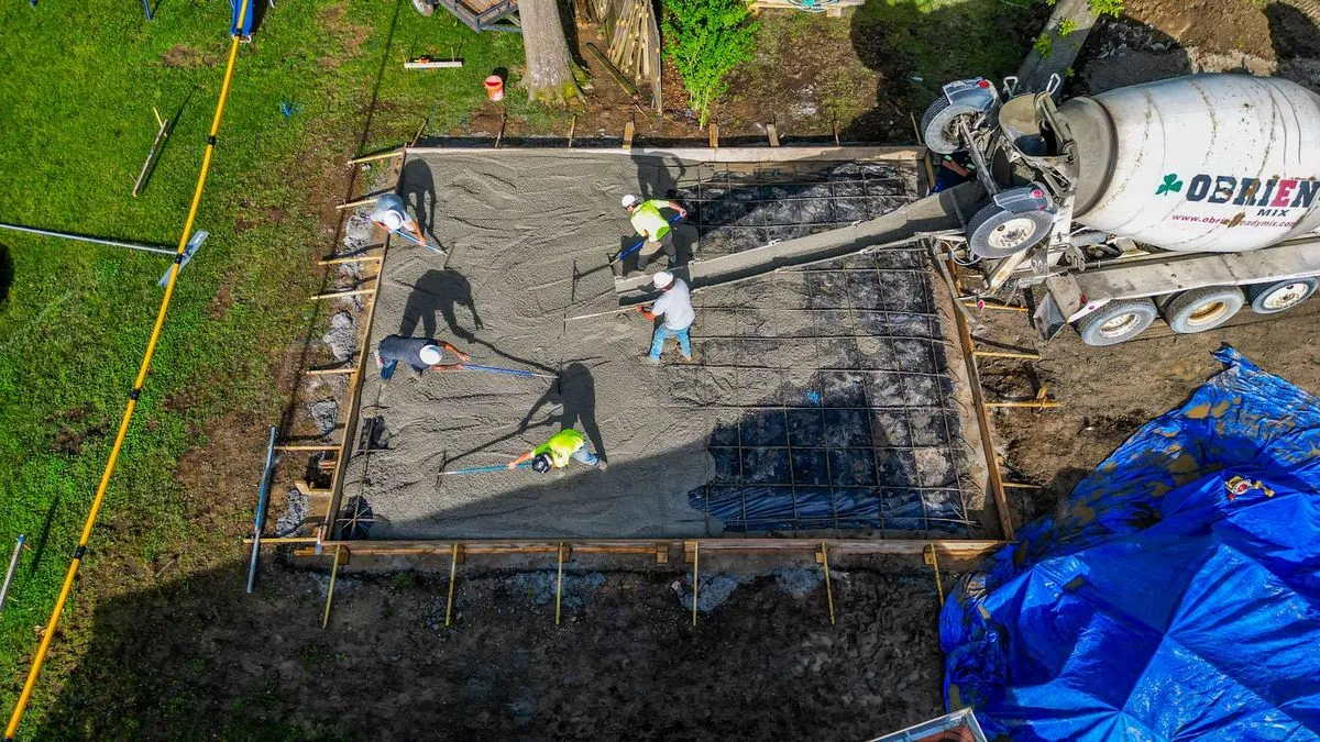 Crew pouring concrete slab with mixer truck on site